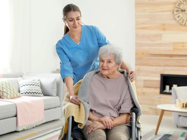 Nurse covering elderly woman in a wheelchair