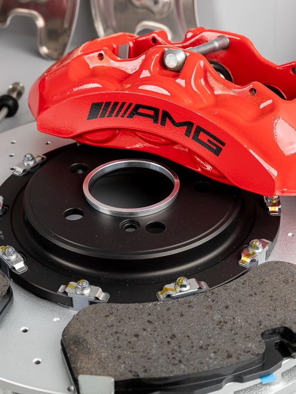 Close-up of a red AMG brake caliper and brake disc components.