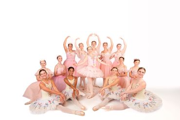 Group of ballerinas posing in pink and floral tutus.