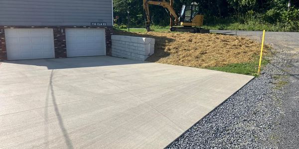 small retaining wall, cement pad, and graded and seeded bank