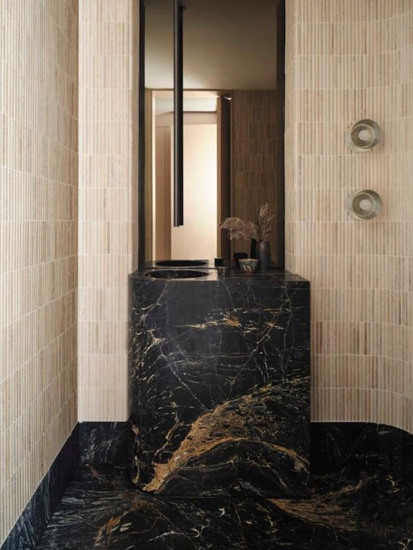 Elegant black marble sink with beige tiled walls.