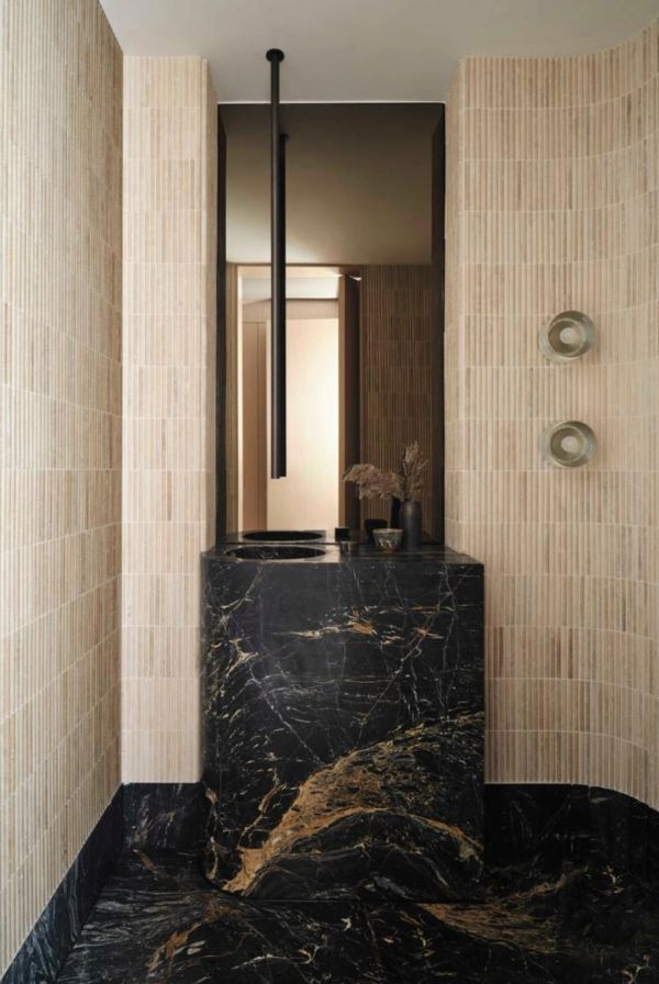 Elegant black marble sink with beige tiled walls.