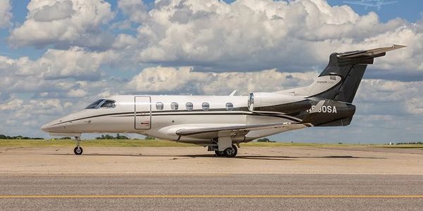 A sleek private jet parked on a runway under a partly cloudy sky.