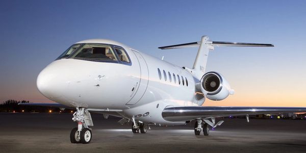 A sleek white private jet parked on the runway at dusk.