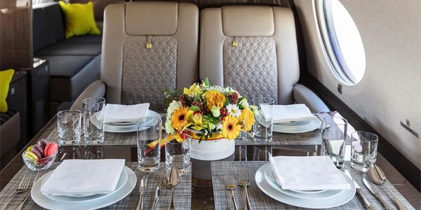 Luxurious dining setup on a private jet with elegant tableware and floral centerpiece.