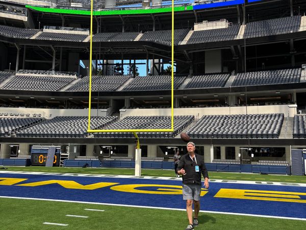 Man tossing a football on a professional football field inside a stadium.