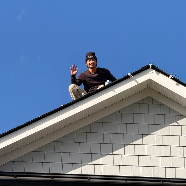 Installer smiling and waving while installing holiday lighting.
