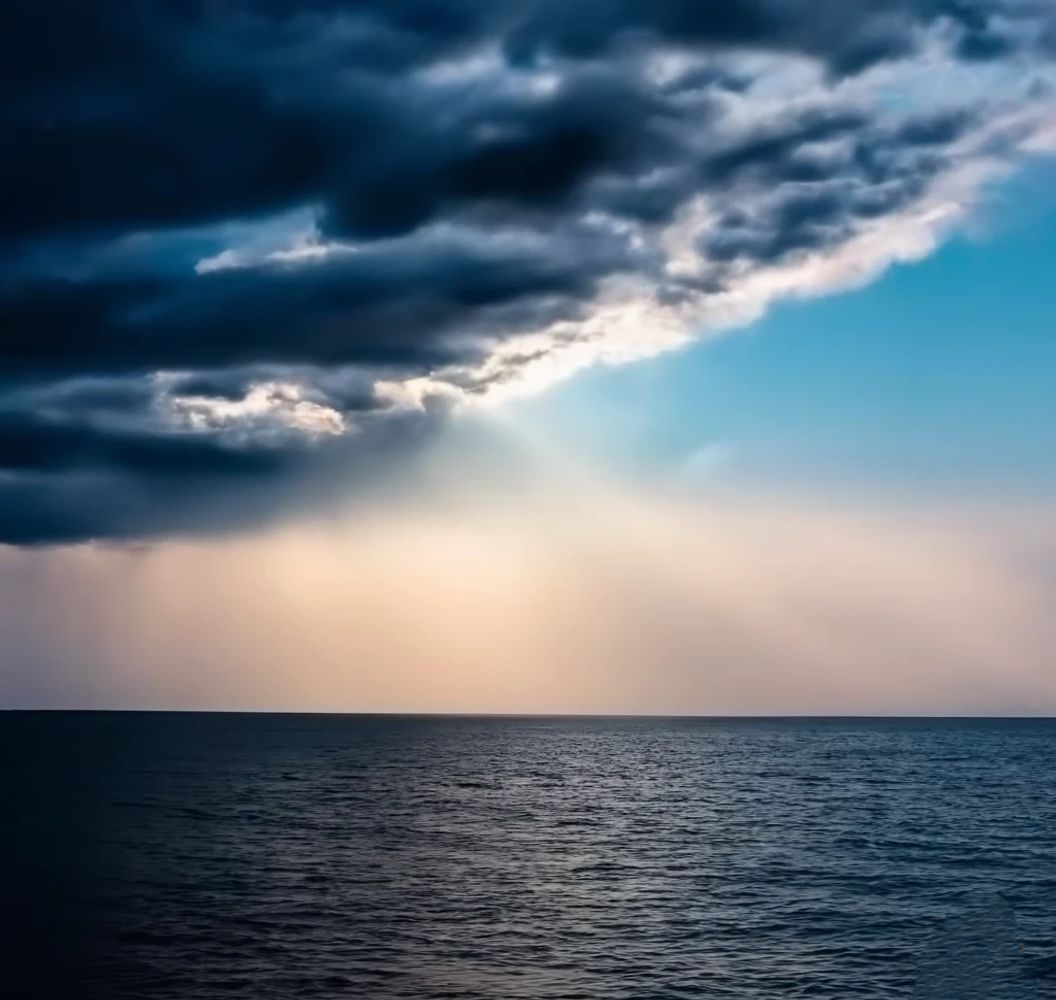 dark storm clouds, with light surrounding them over a calm sea. Every dark cloud has a silver lining