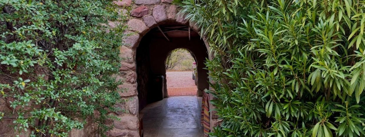 Stone archway surrounded by lush green foliage leading to an outdoor path.