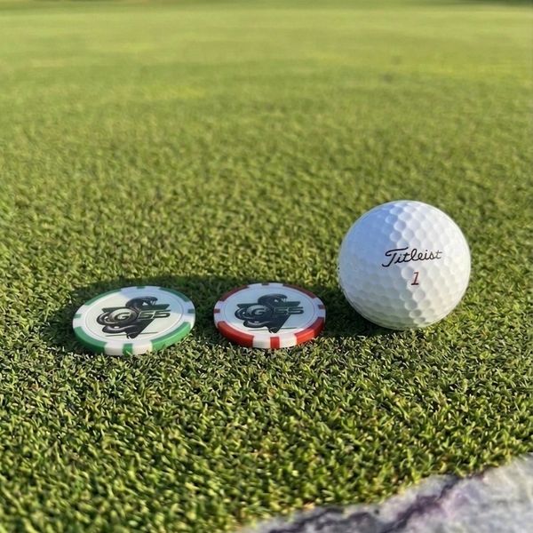 A golf ball and two golf ball markers on a green putting surface.
