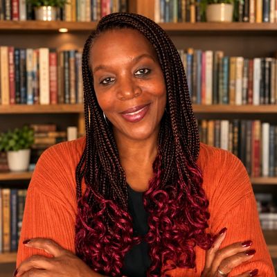 Author Yolanda D. Dawan standing in front of a bookcase filled with books. 