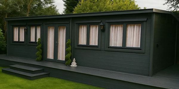 Modern dark green garden shed with large windows and patio doors.