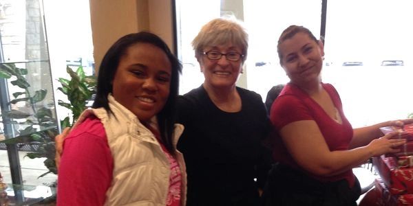 Three women smiling together in an indoor setting