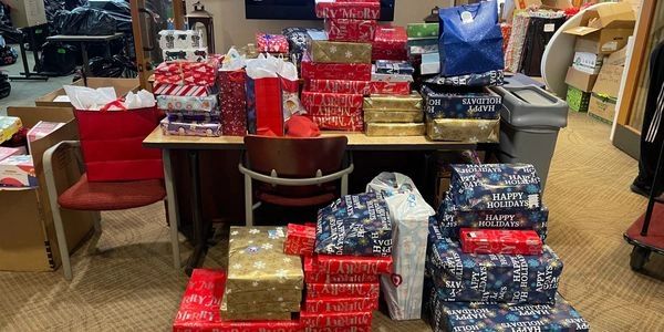 Table and floor covered in many wrapped holiday gifts