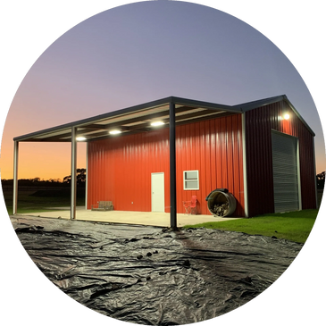 Red metal barn with outdoor lighting at dusk.