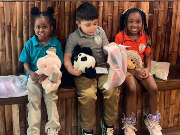 Three children lying with toys, looking ahead