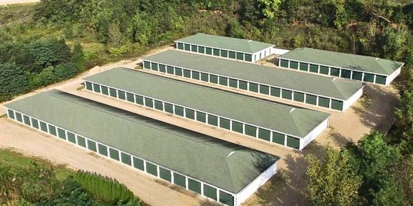 Aerial view of multiple storage unit buildings surrounded by trees.