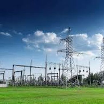 Electric power substation with towers under a blue sky.