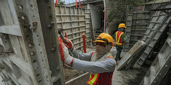 Construction workers wearing safety gear assembling concrete formwork.