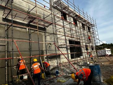 Construction workers in safety gear working on scaffolding around a building.