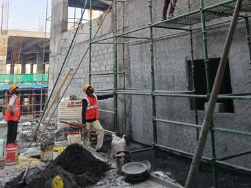 Construction workers inspecting scaffolding on a building site.