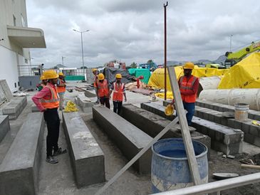 Construction workers in safety gear inspecting concrete beams at a site.