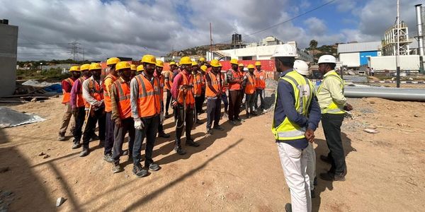 Construction workers in safety gear attending a briefing outdoors.