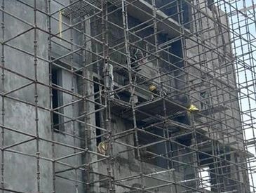 Workers on scaffolding repairing a building exterior.