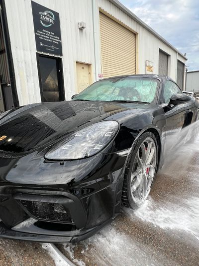 A black sports car being washed outside a garage.