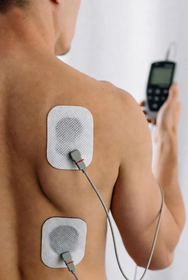 Man using TENS unit pads on his back for pain relief.