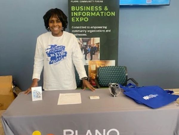 Woman stands behind a table at a business expo booth in Plano.