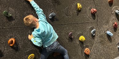 Child climbing an indoor rock wall.