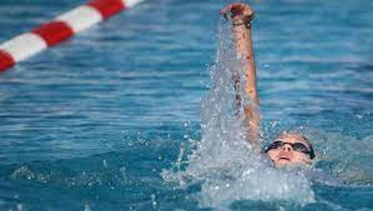 Swimmer performing a backstroke in a pool with goggles on.