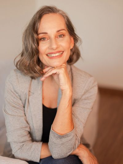 Mulher sorridente com cabelo grisalho e blazer cinza.