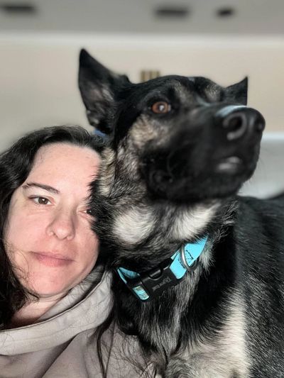A woman cuddles with her German Shepherd dog indoors.