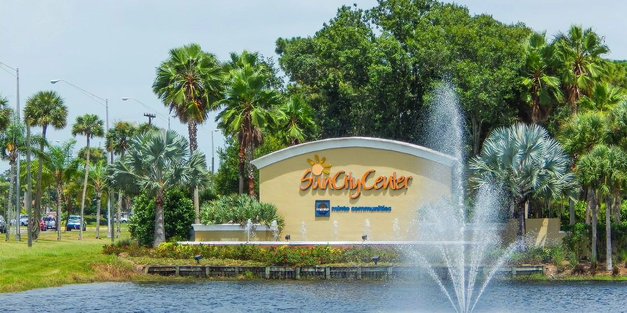 Sun City Center entrance sign with water fountain and palm trees.