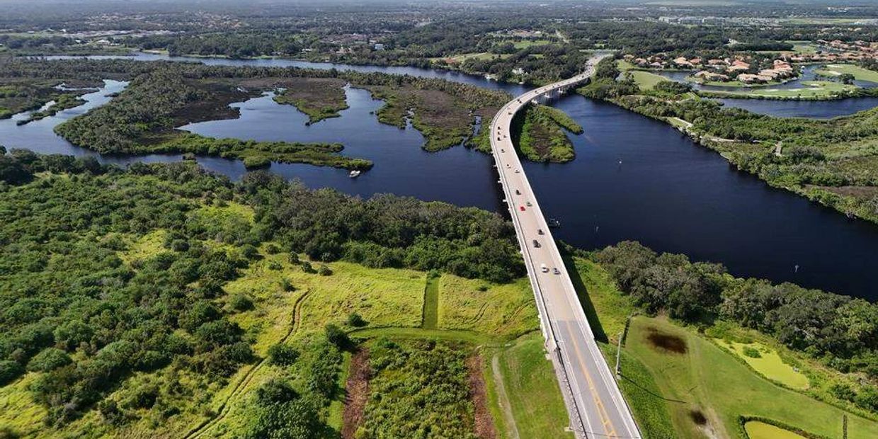A bridge crosses over a river surrounded by green fields and trees.