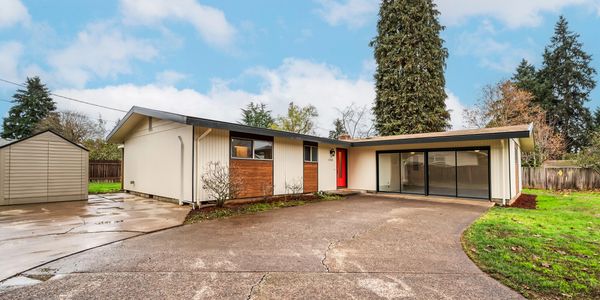Mid-century modern house with a red door and large glass garage doors.