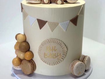 Minimalist beige baby shower cake with bunting and macarons.