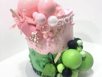 A pink and green balloon decorated cake.