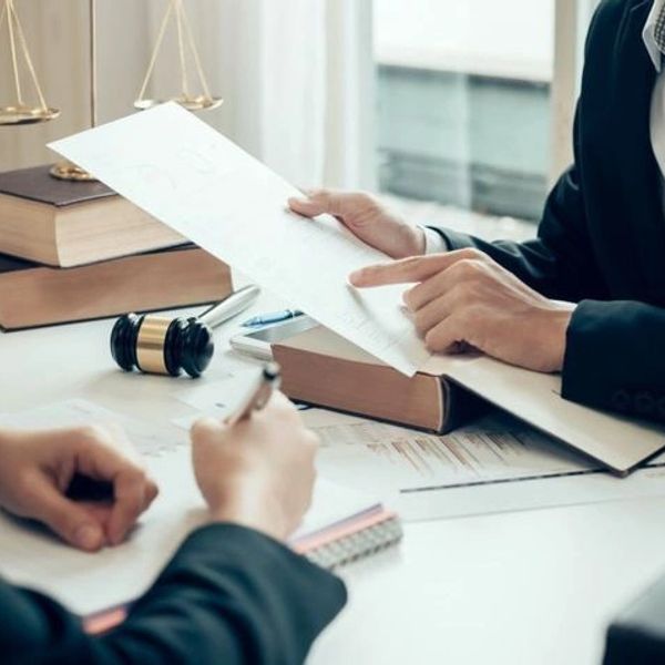 Two people discussing legal documents in an office with law books and a gavel.