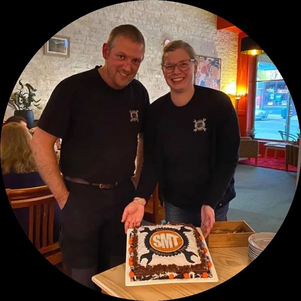 Two people smiling with a decorated cake at a celebration.