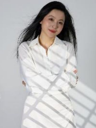 Young woman in a white jacket and pants, with dark, black hair smiling at the camera. 