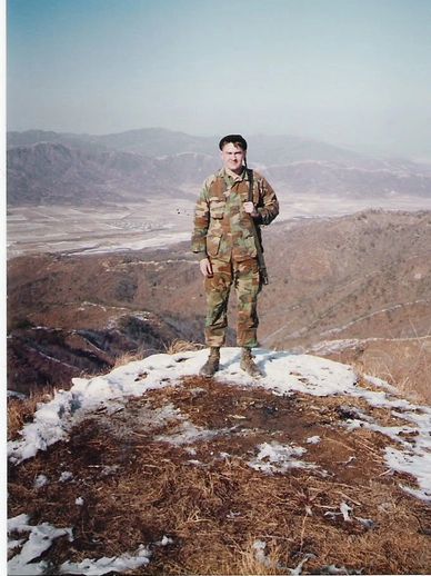 Soldier in camouflage on a hill in a mountainous area.