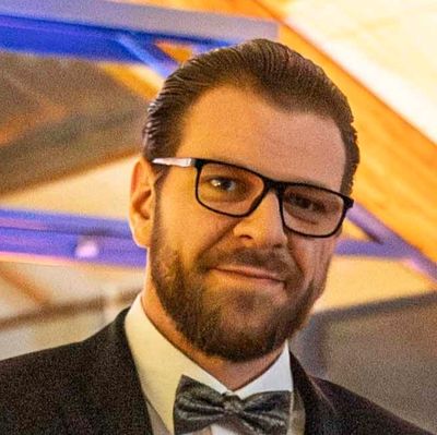 Mann mit Brille und Fliege lächelt in die Kamera.