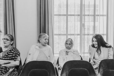 Four women sitting and talking in a bright room with large windows.