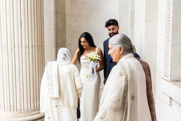 Bride greeting elderly women outside a classical building.