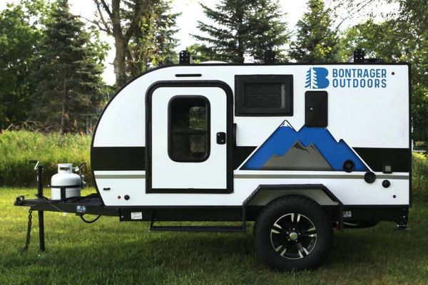 Compact white and black travel trailer with mountain graphic and Bontrager Outdoors logo.