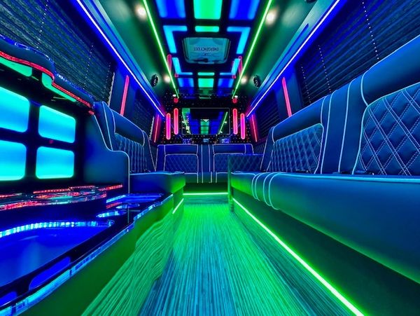 Interior of a neon-lit luxury party bus with comfortable seating.
