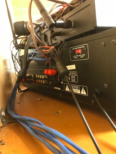 Back view of an audio/video receiver with connected cables and microphones.